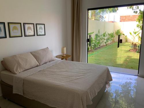ein Schlafzimmer mit einem Bett und einem großen Fenster in der Unterkunft Casa dos cajueiros in Paracuru