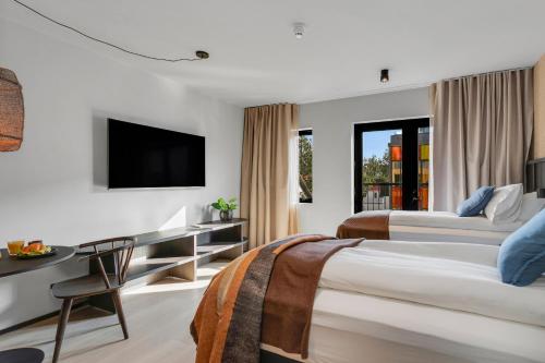 a hotel room with two beds and a desk and a television at Strand Hotel Apartments in Hafnarfjördur