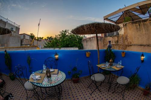 two tables and chairs on a patio with a blue wall at Dar Lalamoune in Fès