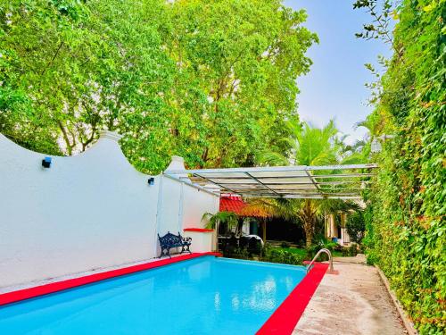 a swimming pool in front of a white building with trees at Casa Jalisco, Campeche 2 in Campeche