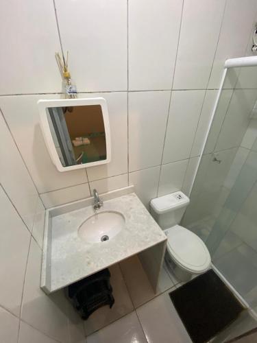 a bathroom with a sink and a toilet and a mirror at Vale do Pontal Angra Suites in Angra dos Reis