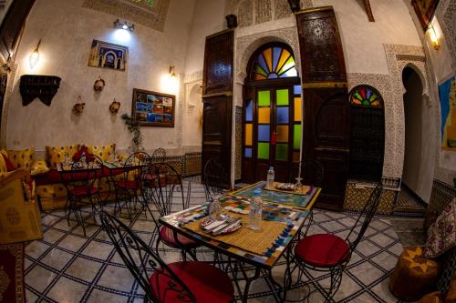 a restaurant with tables and chairs and stained glass windows at Dar Lalamoune in Fès