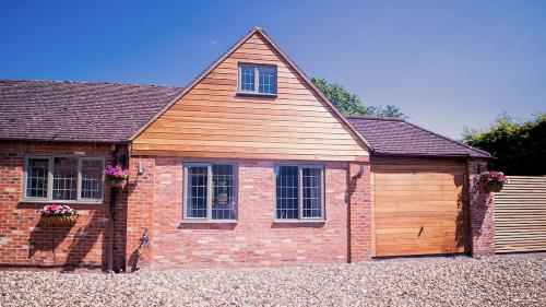 a red brick house with a wooden garage at Stylish Stratford upon Avon Stay - Gated Parking - Sleeps 6 in Stratford-upon-Avon