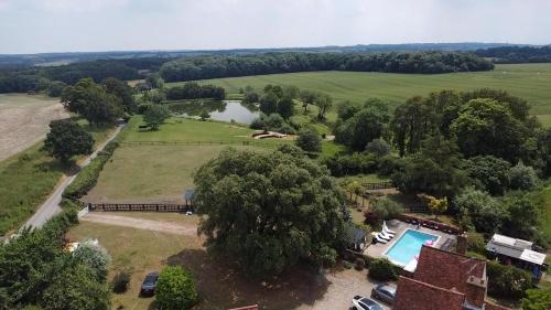 an aerial view of a house with a pool and a lake at Grade II Listed Farmhouse, Pool, Hot Tub, Games Room, Celebration Hall, Car Park, 10ppl, 45 min from Central London in Stapleford Tawney