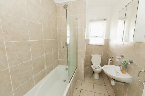a bathroom with a tub and a toilet and a sink at Muizi Hideaway in Muizenberg