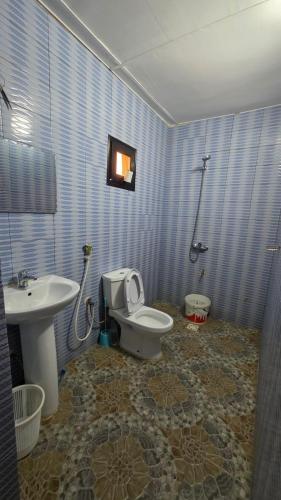 a blue tiled bathroom with a toilet and a sink at FARAFINA KEUR DAMEL Toubakouta in Toubakouta