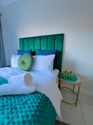 a bed with a green headboard and a side table at Blyde Lagoon in Pretoria