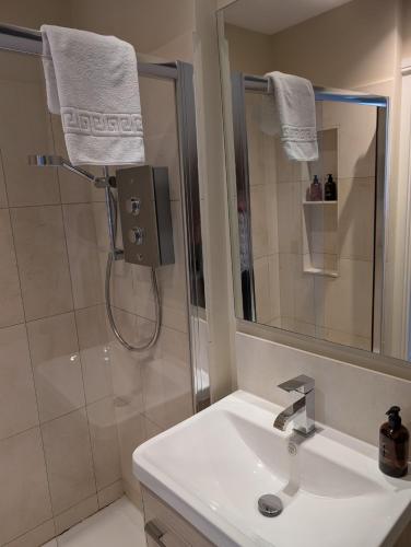 a bathroom with a sink and a shower with a mirror at The Crown at Shipton in Shipton under Wychwood