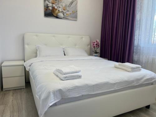 a bedroom with a white bed with towels on it at Anastasia Dragonul Roșu Spitalul Fundeni in Dobroeşti