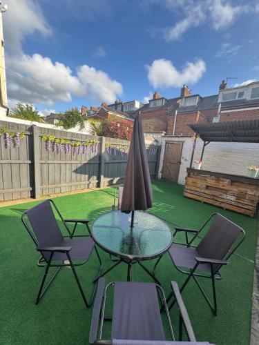 a glass table with two chairs and a umbrella at Excellent, comfortable location to visit Belfast in Holywood