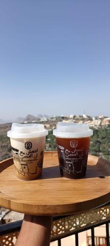 two cups of coffee sitting on a wooden table at Hissen Al-Misfah in Misfāh