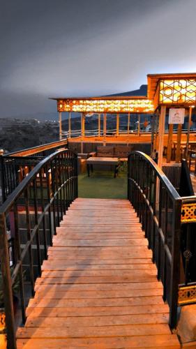 a wooden walkway leading to a building with a bench at Hissen Al-Misfah in Misfāh