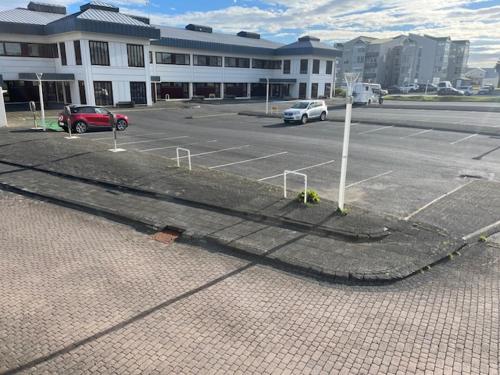 a parking lot with cars parked in front of a building at A. Bernhard Guest House in Keflavík