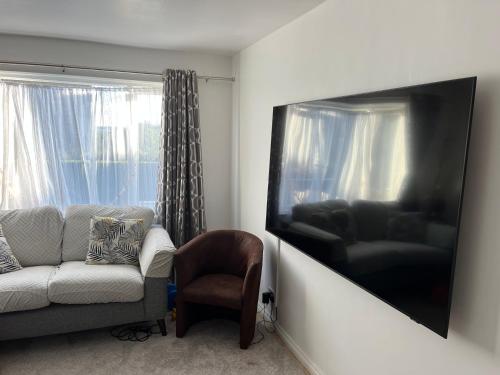 a living room with a couch and a flat screen tv at Garden house in Canterbury