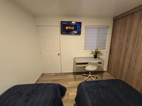 a bedroom with two beds and a desk and a television at AH Hotel in Antofagasta