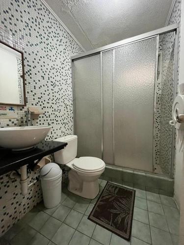 a bathroom with a shower and a toilet and a sink at Gaudy's Hotel in San José