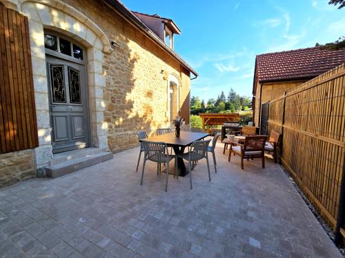 a patio with a table and chairs next to a building at Clos du Tilleul - Spa couvert et havre de paix in Sarlat-la-Canéda
