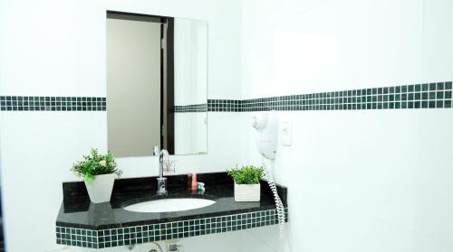 a bathroom with a sink and a mirror at Tezla Hotel in Primavera do Leste