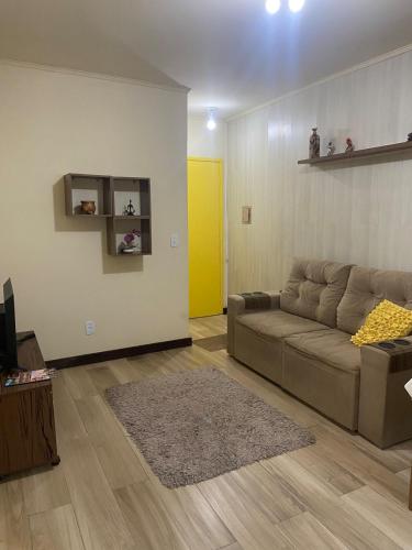 ein Wohnzimmer mit Sofa und gelber Tür in der Unterkunft Apartamento central confortável in Pelotas