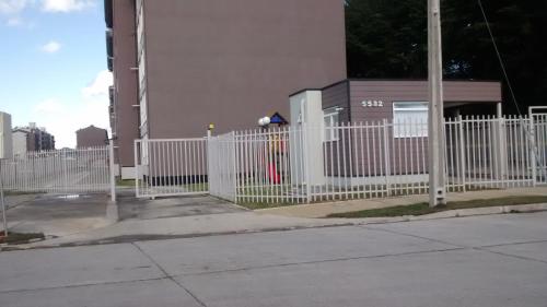 a white picket fence in front of a building at Departamentos Rohe in Puerto Montt