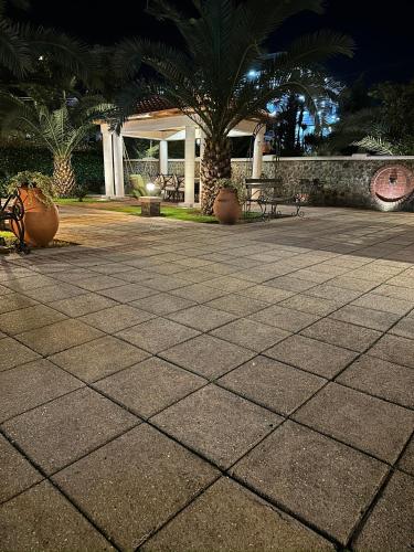 a stone patio with palm trees and benches at night at Kobuleti VILLA SKAZOCNI DVORIK VIP in K'obulet'i