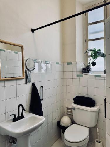 a white bathroom with a toilet and a sink at Casa Zapata, Mérida Yucatán in Mérida