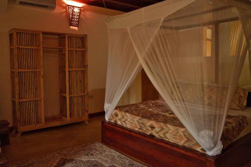 a bedroom with a canopy bed with curtains at Kidoti Bay in Kidoti