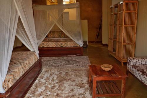 a bedroom with two beds with curtains and a table at Kidoti Bay in Kidoti