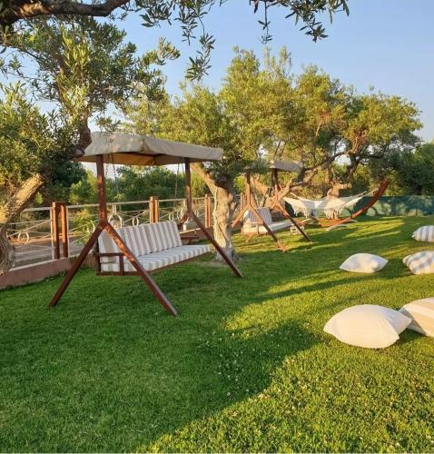 a park with a swing and an umbrella on the grass at Aroma studios&apartments 2 in Vourvourou