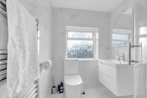 Un baño blanco con inodoro y lavabo. en 4 Bed - Sleeps 8 - Free Parking - Garden, en Dagenham