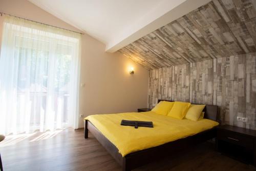 een slaapkamer met een geel bed en een groot raam bij Avanti Apartman - Avanti Tutti in Balatonboglár