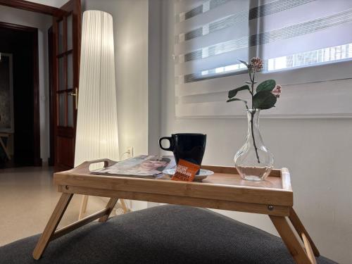 a wooden table with a vase with a flower in it at Casa Azacanes in Sanlúcar de Barrameda