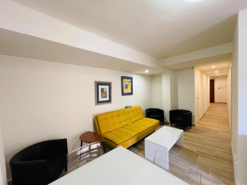 a living room with a yellow couch and black chairs at Palacio de Larrinaga in Zaragoza