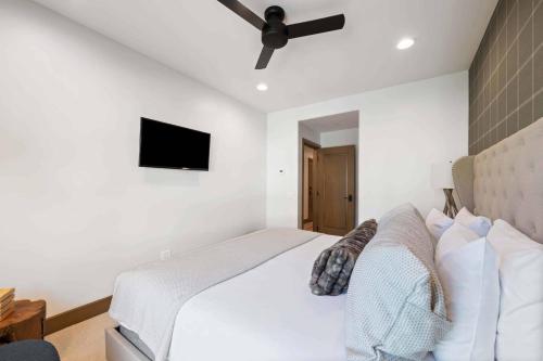 a bedroom with a white bed with a ceiling fan at Village Hall 13 by East West Hospitality in Beaver Creek