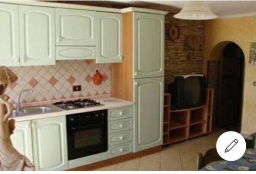 Una cocina con gabinetes blancos, un fregadero y un microondas. en Appartamento Mariolu 2, en Santa Maria Navarrese