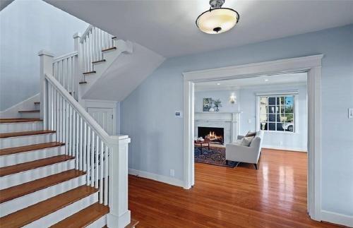 ロングビーチにあるHistoric Three-Bedroom Coastal Home with Expansive Ocean Viewsの暖炉付きのリビングルームにある白い階段