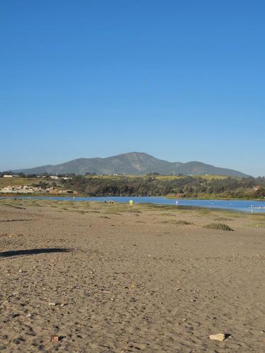 a beach with water and mountains in the background at Bocamar Aparthotel in Viña del Mar