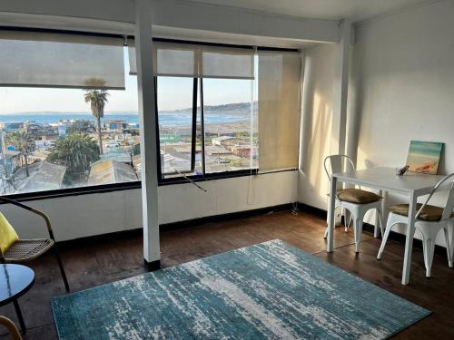 a living room with a table and chairs and a large window at Bocamar Aparthotel in Viña del Mar