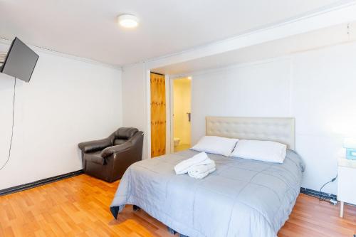 a bedroom with a bed and a chair and a television at Bocamar Aparthotel in Viña del Mar