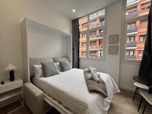 a bedroom with a large white bed with two windows at Gabika Apartment 2 in Bilbao