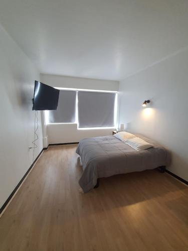 a white room with a bed and a television at Bocamar Aparthotel in Viña del Mar