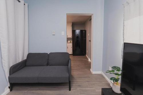 a living room with a couch and a black refrigerator at Avenir Centre Suite - Near NBCC - Large Garden in Moncton