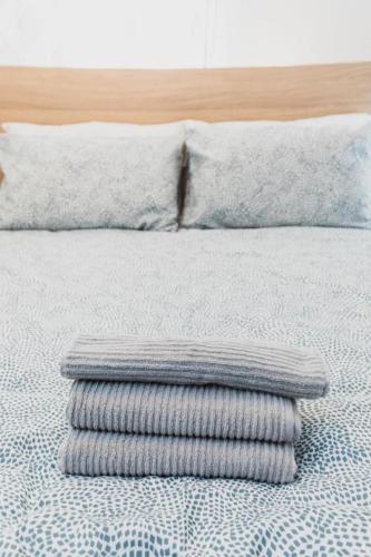 a stack of towels on a bed with a pillow at Avenir Centre Suite - Near NBCC - Large Garden in Moncton