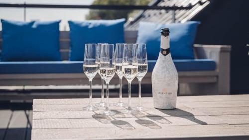 a bottle of wine and four wine glasses on a table at Intens Genieten aan het Sneekermeer in Offingawier
