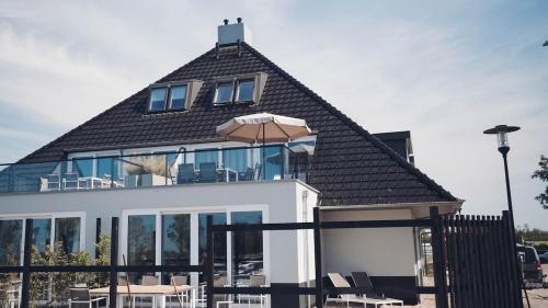 a house with a roof with windows and an umbrella at Intens Genieten aan het Sneekermeer in Offingawier