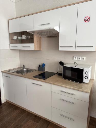 a white kitchen with a microwave and a sink at Kovarik Apartments I in Olomouc