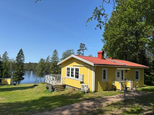 a yellow house on the side of a lake at Stunning lakeside home with sauna surrounded by nature in Sandared