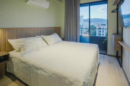 a bedroom with a white bed and a large window at BRENT 30 Living in Medellín