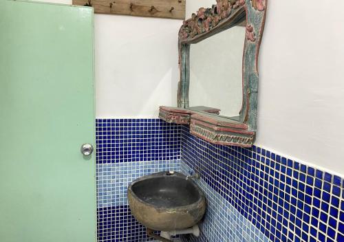 a mirror and a bowl in a bathroom with blue tiles at PRO Batu Embun Pagi Hotel in Punten