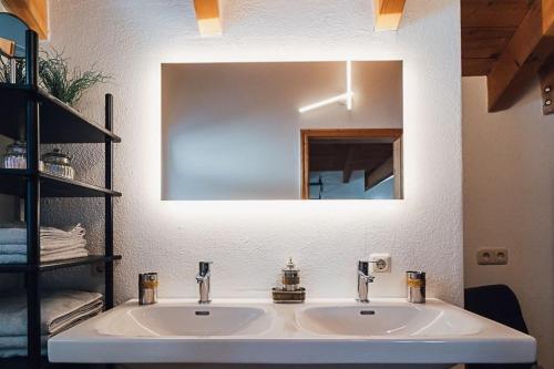 Un lavabo de baño con un espejo grande encima. en Urlaub im alten E-Werk, en Görisried